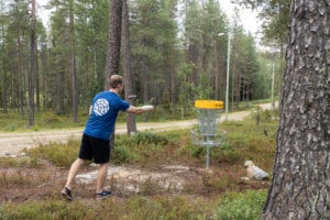 Mies heittämässä frisbeegolfia