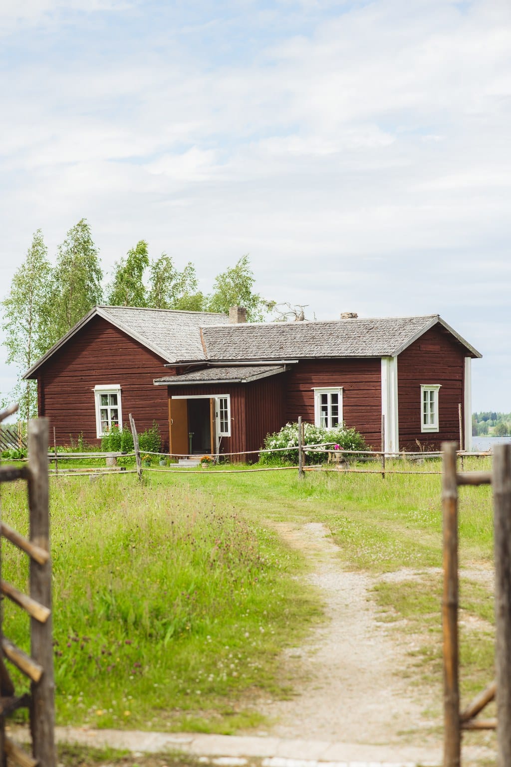 Punainen hirsirakennus ulkoa kuvattuna kesällä