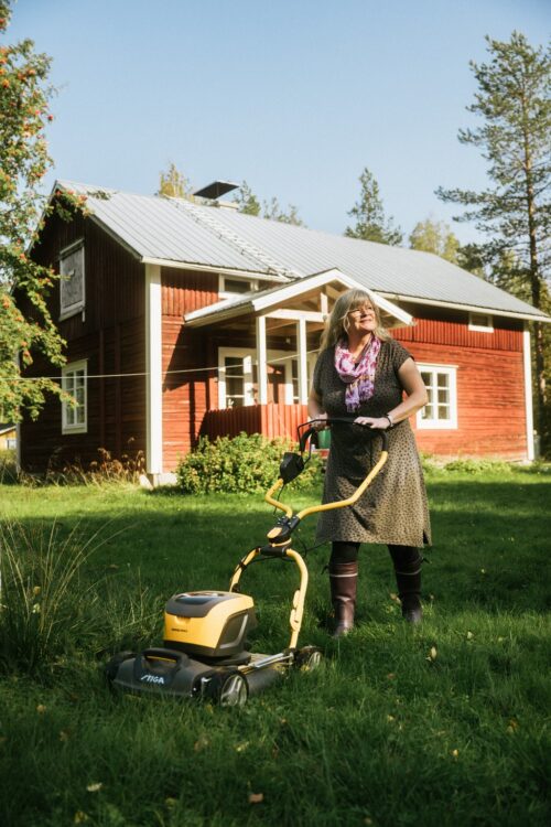 Maija Junno ajamassa nurmikkoa pihallaan.