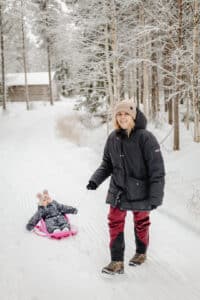 Äiti vetää lasta pulkassa 