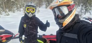 Kaksi miestä moottorikelkkakypärät päässä.