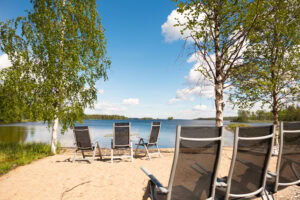 Rantatuoleja hiekkarannalla, järvimaisema