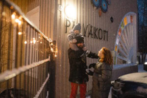 Perhe lumisessa säässä päiväkodin edessä.